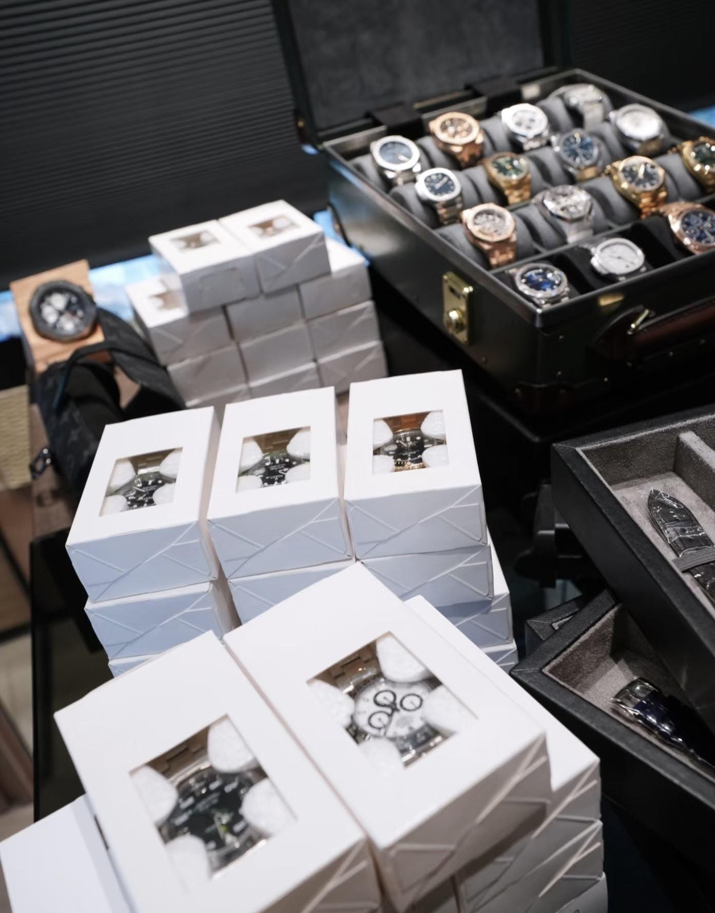 Stacked boxed watches and a display case of wholesale stock